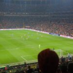 Home Thrilling soccer match at a packed Istanbul stadium with vibrant crowd and atmospheric lighting.