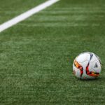 Home A vibrant soccer ball resting on a pristine grass field beside a white sideline.