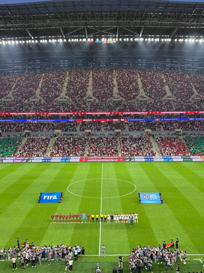 Services Aerial view of a football match kickoff in a vibrant, full stadium.